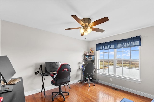 home office with hardwood / wood-style flooring, ceiling fan, and a water view