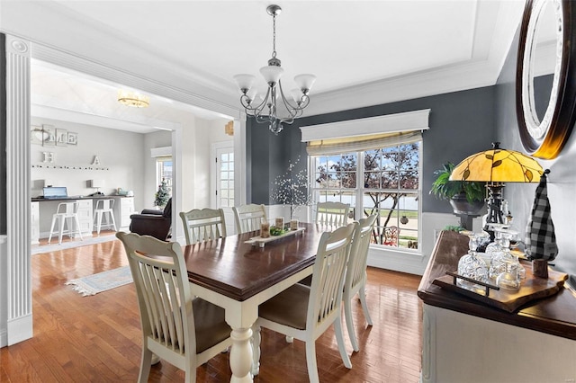 dining area with crown molding, a chandelier, and hardwood / wood-style flooring