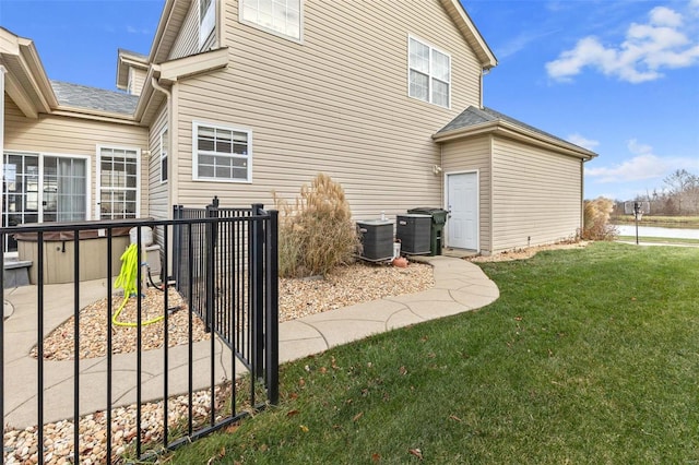 rear view of property featuring a yard and cooling unit