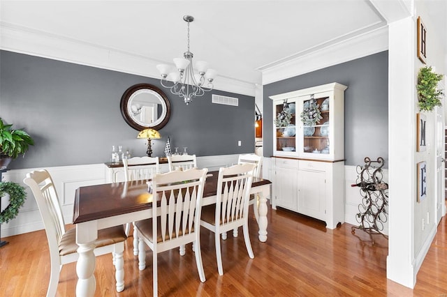 dining area with a chandelier, hardwood / wood-style floors, and crown molding