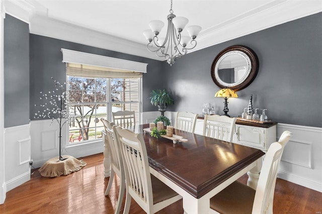 dining area with hardwood / wood-style floors, a notable chandelier, and ornamental molding