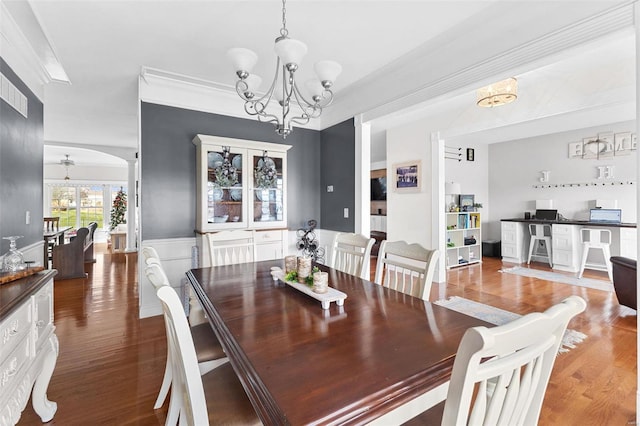 dining area with crown molding, hardwood / wood-style floors, and an inviting chandelier