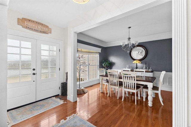 dining space featuring hardwood / wood-style floors, a chandelier, crown molding, and french doors