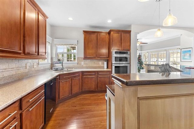 kitchen featuring backsplash, sink, a kitchen island, light hardwood / wood-style floors, and stainless steel double oven