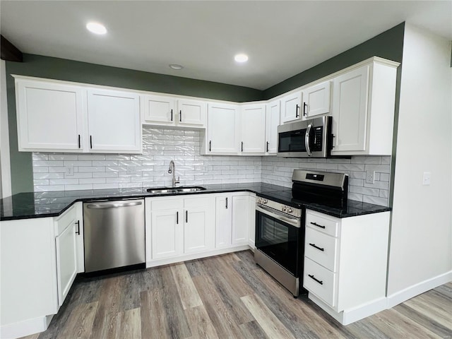 kitchen featuring white cabinetry, sink, light hardwood / wood-style floors, and appliances with stainless steel finishes