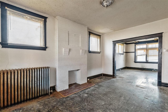 spare room with radiator heating unit, a textured ceiling, and a wealth of natural light