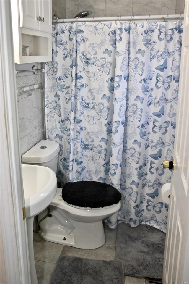 bathroom featuring tile patterned flooring, toilet, tile walls, and walk in shower