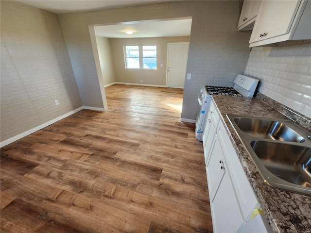 kitchen featuring gas range, sink, white cabinets, and light wood-type flooring