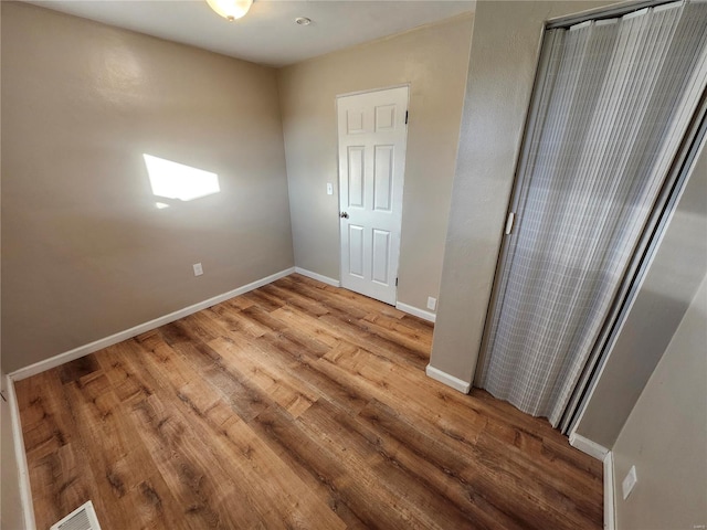 unfurnished bedroom with hardwood / wood-style flooring, a closet, and a skylight