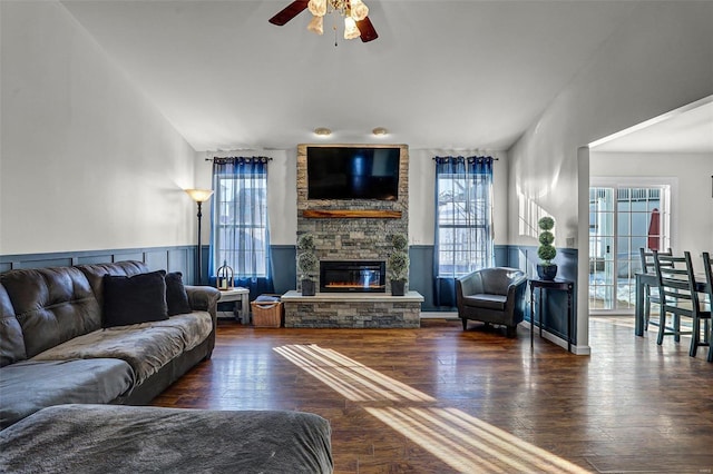 living room with dark wood-type flooring, ceiling fan, a fireplace, and plenty of natural light