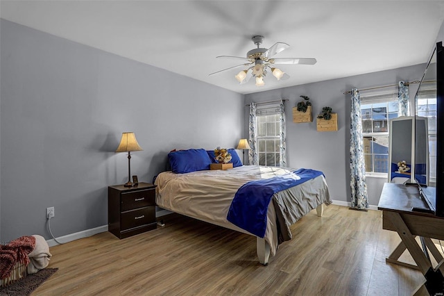 bedroom featuring ceiling fan, wood-type flooring, and multiple windows