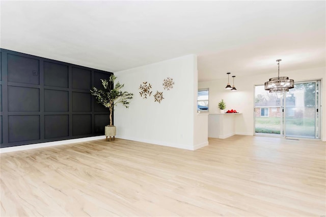 unfurnished room featuring a chandelier and light hardwood / wood-style flooring