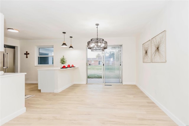 unfurnished dining area featuring a chandelier and light wood-type flooring