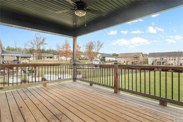 wooden terrace with ceiling fan, a water view, and a yard