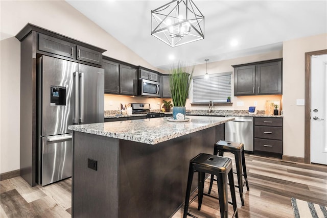 kitchen featuring a chandelier, pendant lighting, a breakfast bar, a kitchen island, and appliances with stainless steel finishes