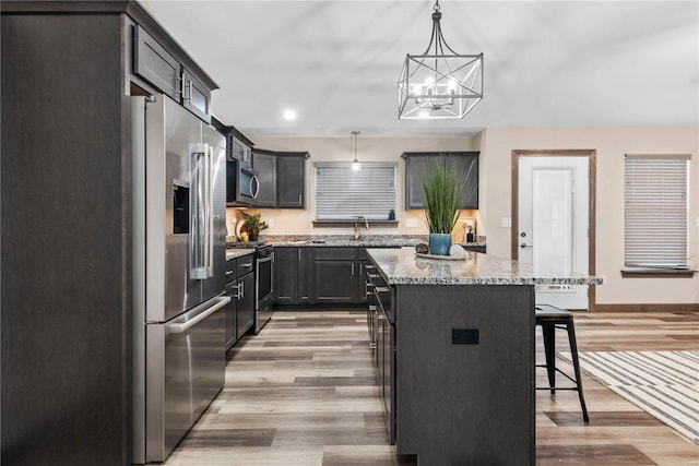 kitchen featuring a breakfast bar, an inviting chandelier, hanging light fixtures, appliances with stainless steel finishes, and a kitchen island