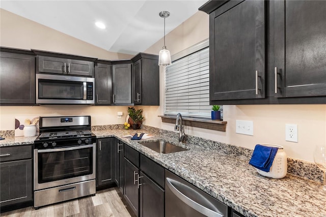 kitchen with lofted ceiling, hanging light fixtures, sink, light hardwood / wood-style flooring, and appliances with stainless steel finishes