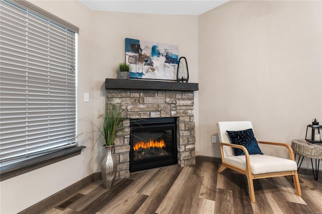 sitting room with hardwood / wood-style flooring and a stone fireplace