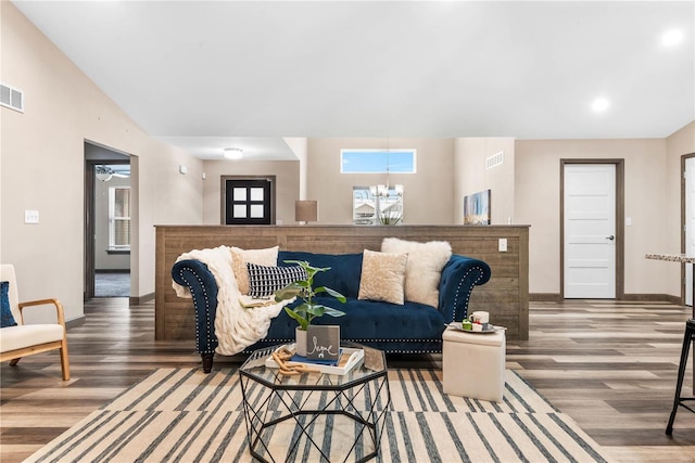 living room with vaulted ceiling, wood-type flooring, and an inviting chandelier