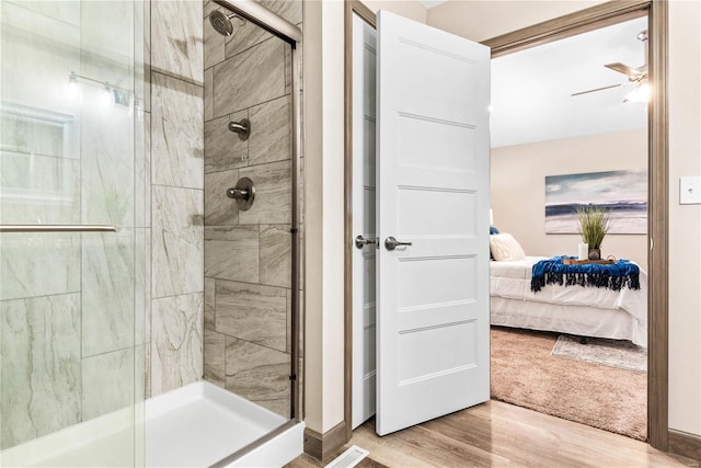 bathroom featuring ceiling fan, hardwood / wood-style floors, and an enclosed shower