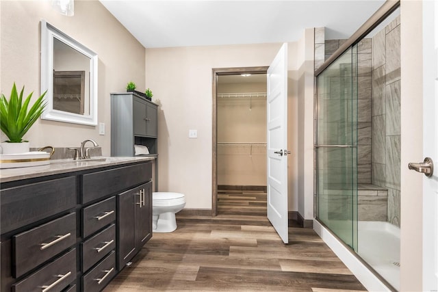 bathroom with hardwood / wood-style flooring, toilet, vanity, and walk in shower