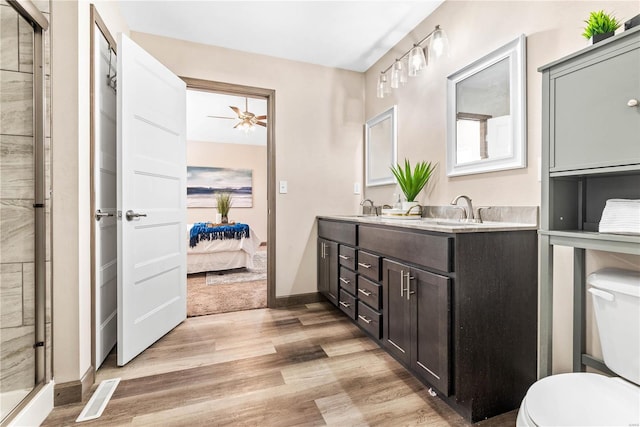 bathroom featuring hardwood / wood-style floors, vanity, ceiling fan, toilet, and an enclosed shower