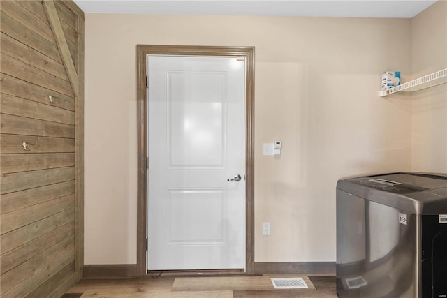 laundry area featuring light hardwood / wood-style floors and wooden walls