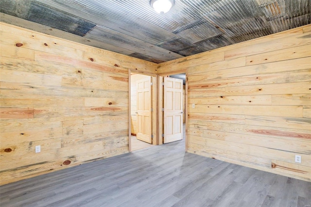 unfurnished room with hardwood / wood-style flooring and wooden walls