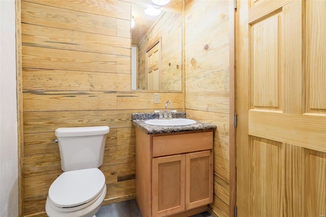 bathroom with vanity, toilet, and wooden walls