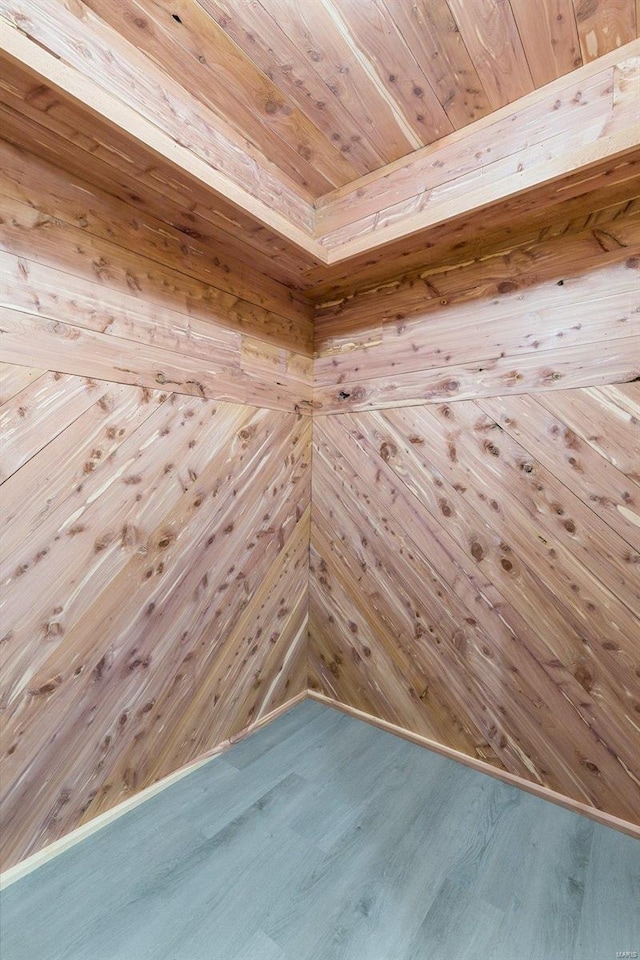 empty room with wooden walls, wood ceiling, and hardwood / wood-style flooring