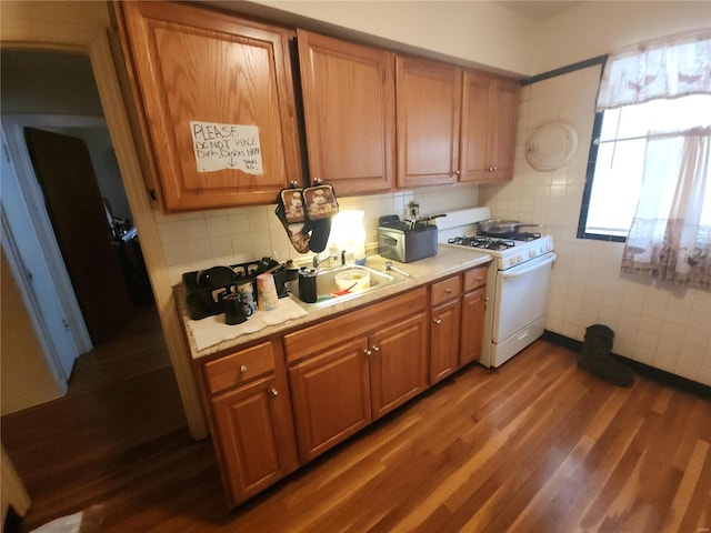 kitchen with sink, white gas range oven, tile walls, backsplash, and dark hardwood / wood-style floors