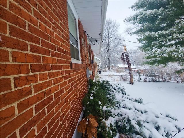 view of snow covered exterior with brick siding