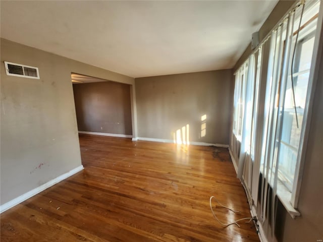 spare room featuring wood finished floors, visible vents, and baseboards