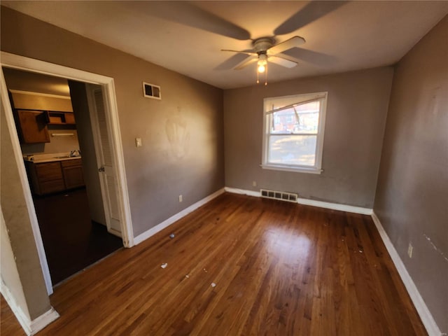 unfurnished bedroom with dark wood-style floors, a sink, visible vents, and baseboards