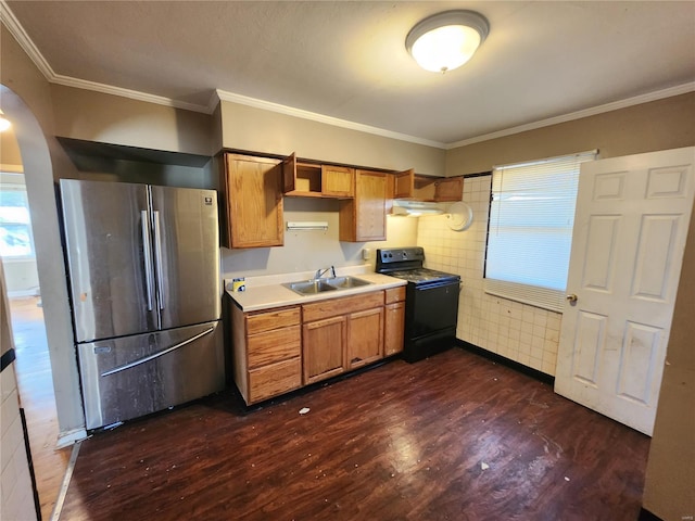 kitchen featuring arched walkways, light countertops, freestanding refrigerator, a sink, and black / electric stove