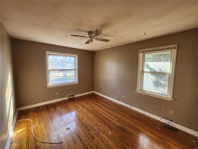 unfurnished room with a ceiling fan, baseboards, visible vents, and dark wood-type flooring