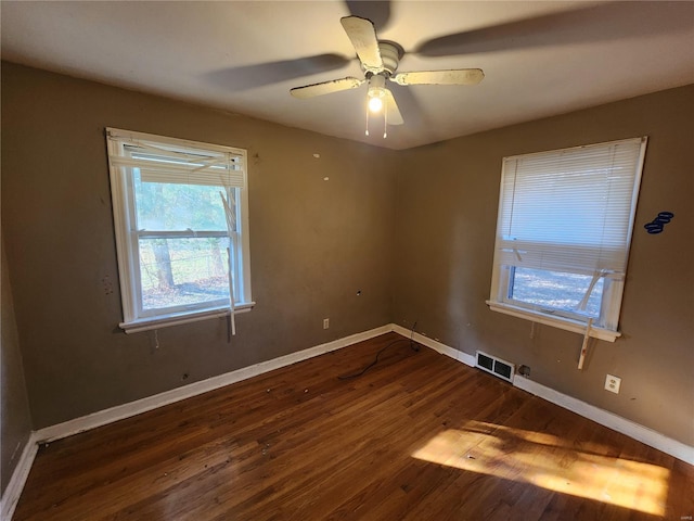 spare room with dark wood-style floors, ceiling fan, visible vents, and baseboards