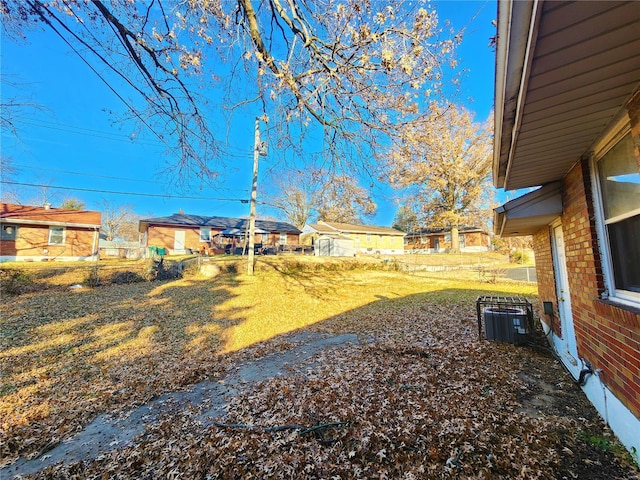 view of yard featuring central AC, fence, and a residential view