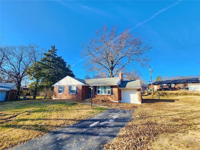 ranch-style home with driveway, a garage, a chimney, a front lawn, and brick siding