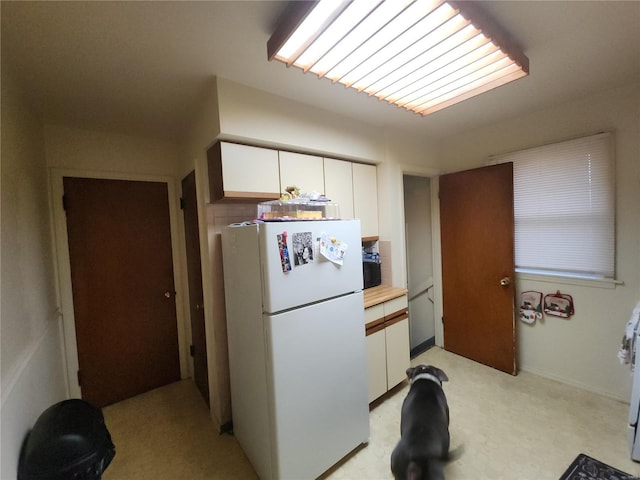 kitchen featuring white cabinets, light countertops, and freestanding refrigerator