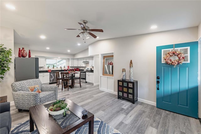 living room featuring ceiling fan, sink, light hardwood / wood-style floors, and lofted ceiling