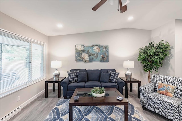 living room featuring baseboard heating, a wealth of natural light, hardwood / wood-style floors, and vaulted ceiling