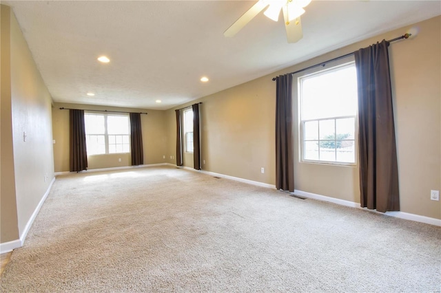 spare room with light carpet, a wealth of natural light, and ceiling fan