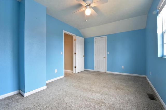 spare room with a wealth of natural light, ceiling fan, light colored carpet, and vaulted ceiling