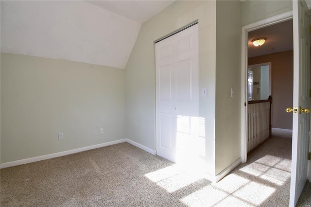 unfurnished bedroom with light carpet, a closet, and lofted ceiling