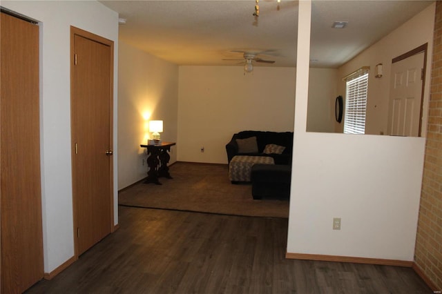 interior space featuring ceiling fan, dark hardwood / wood-style flooring, and brick wall