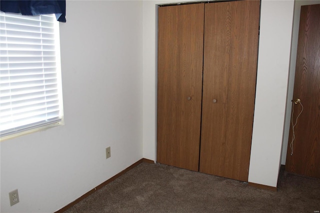 unfurnished bedroom featuring dark carpet and a closet