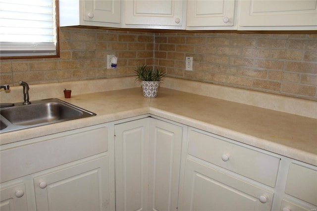 kitchen featuring backsplash, white cabinetry, and sink