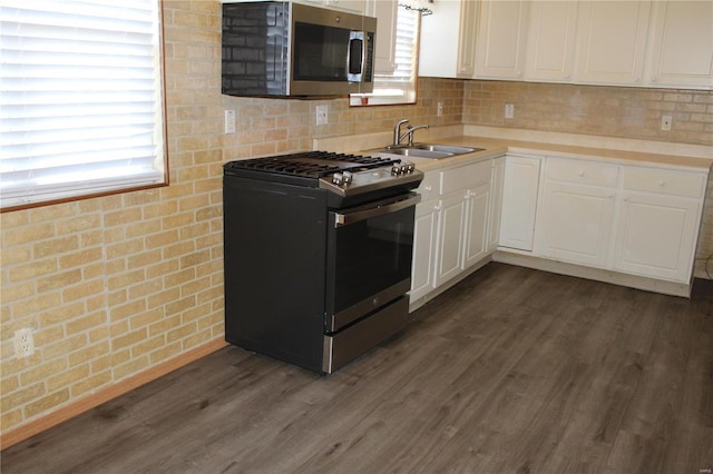 kitchen with appliances with stainless steel finishes, dark hardwood / wood-style floors, white cabinetry, and sink