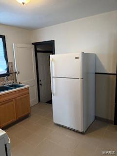 kitchen featuring white refrigerator, light tile patterned floors, and sink